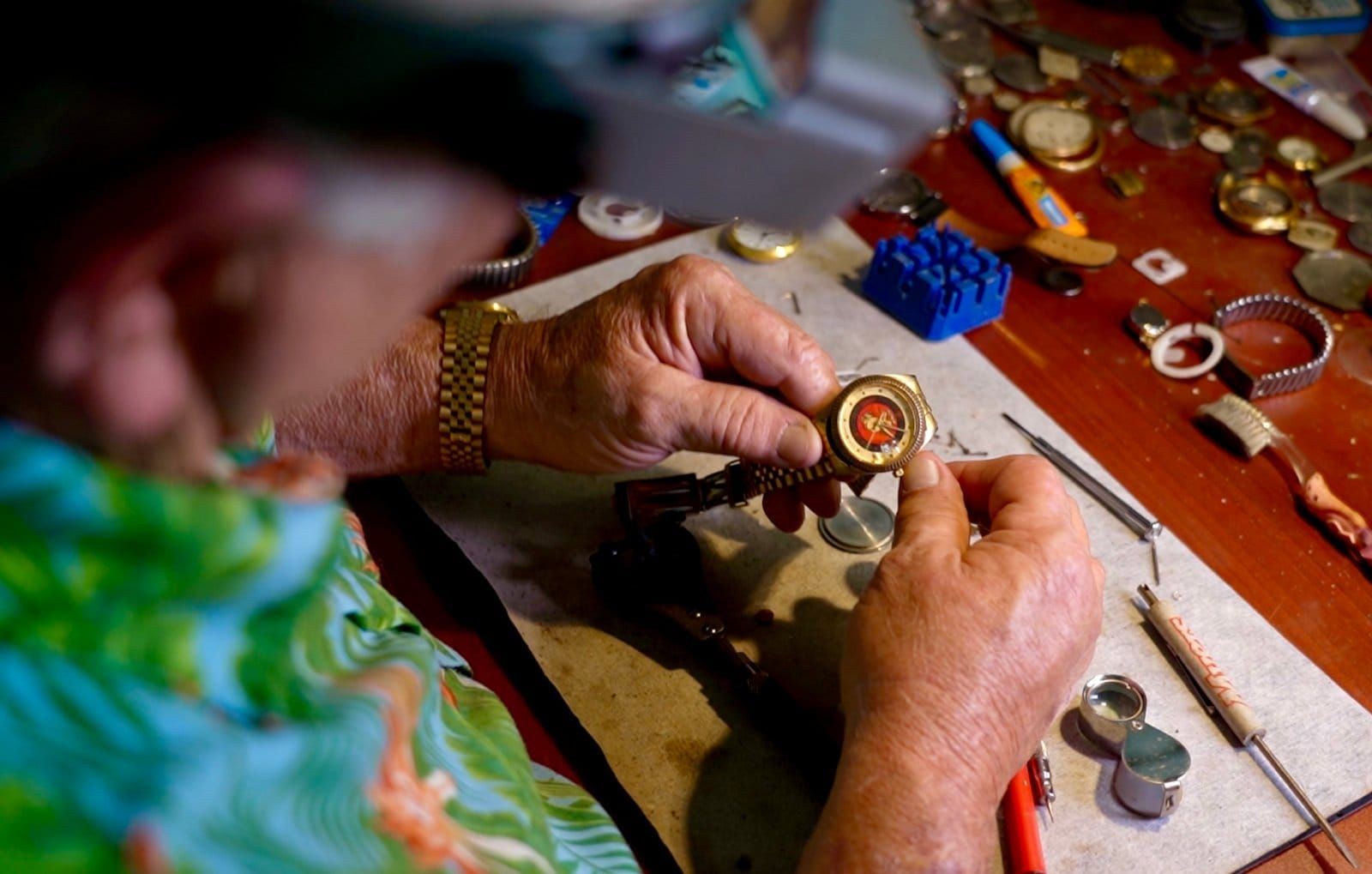 A man changing the battery of a watch he is holding.