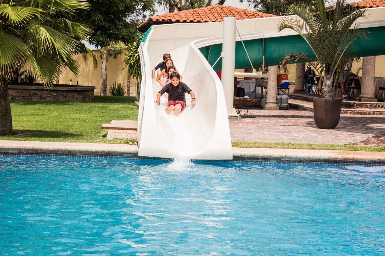 Dos personas se deslizan por un tobogán de aguas bravas hacia una piscina azul.