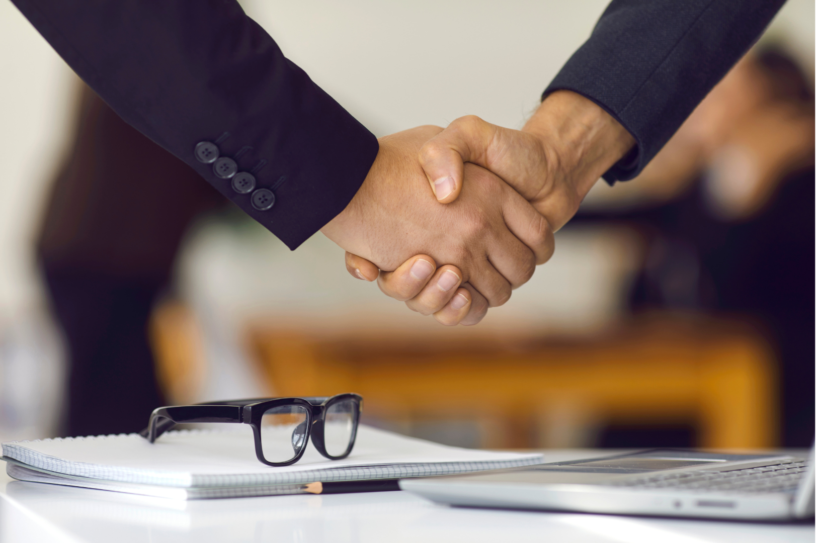 Two people shaking hands, sealing a deal in regards to HR compliance.