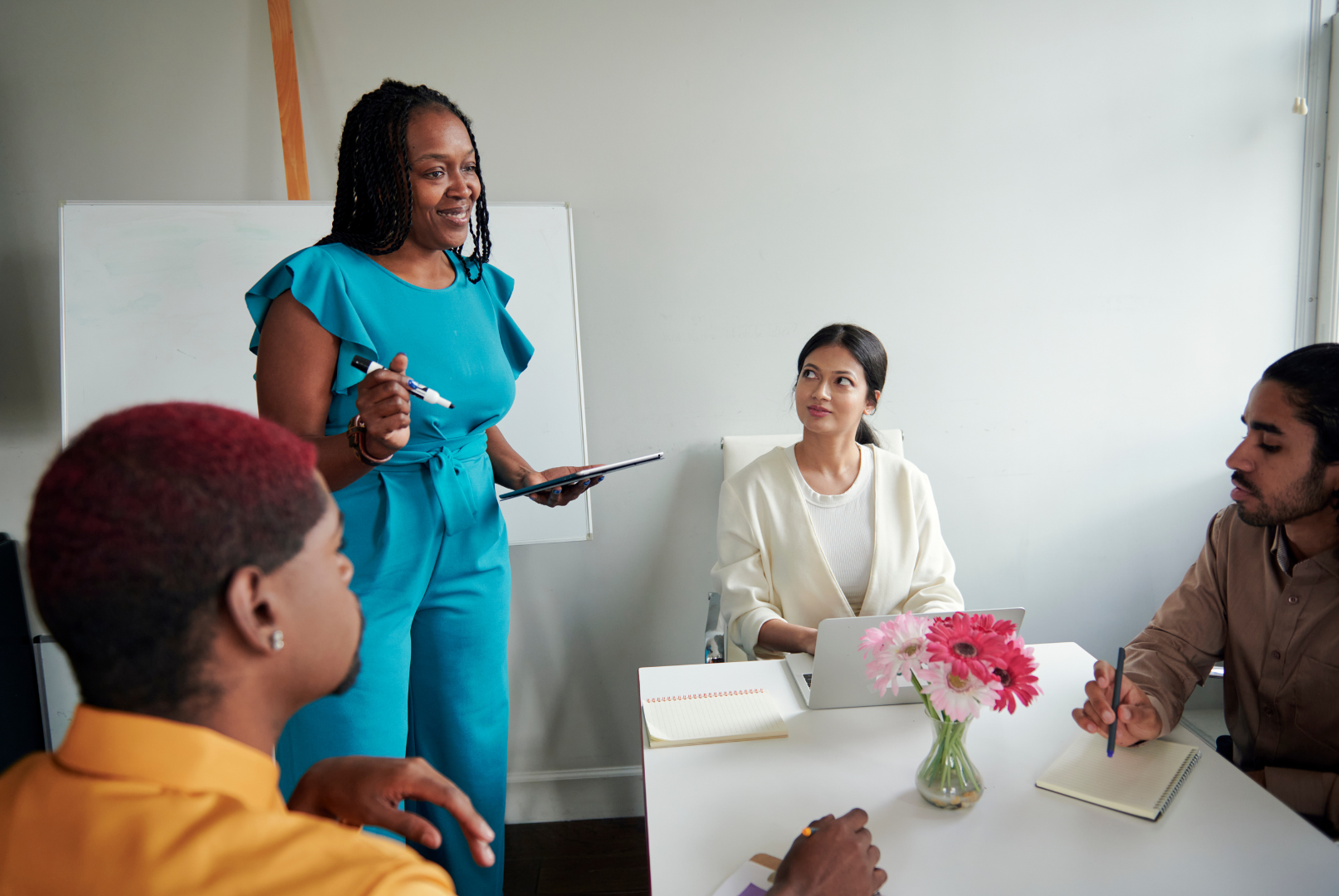 HR consultancy can be a woman in blue giving a presentation to a diverse group seated around a table.