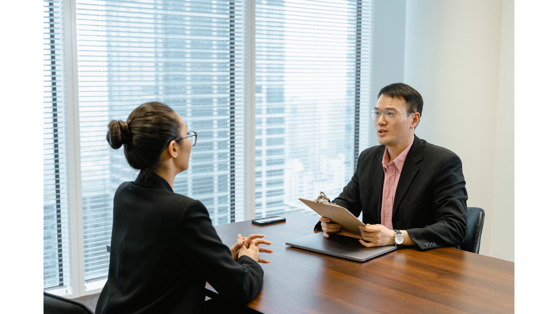 Two people in suits at a table in an office, interviewing with a fractional HR leader.