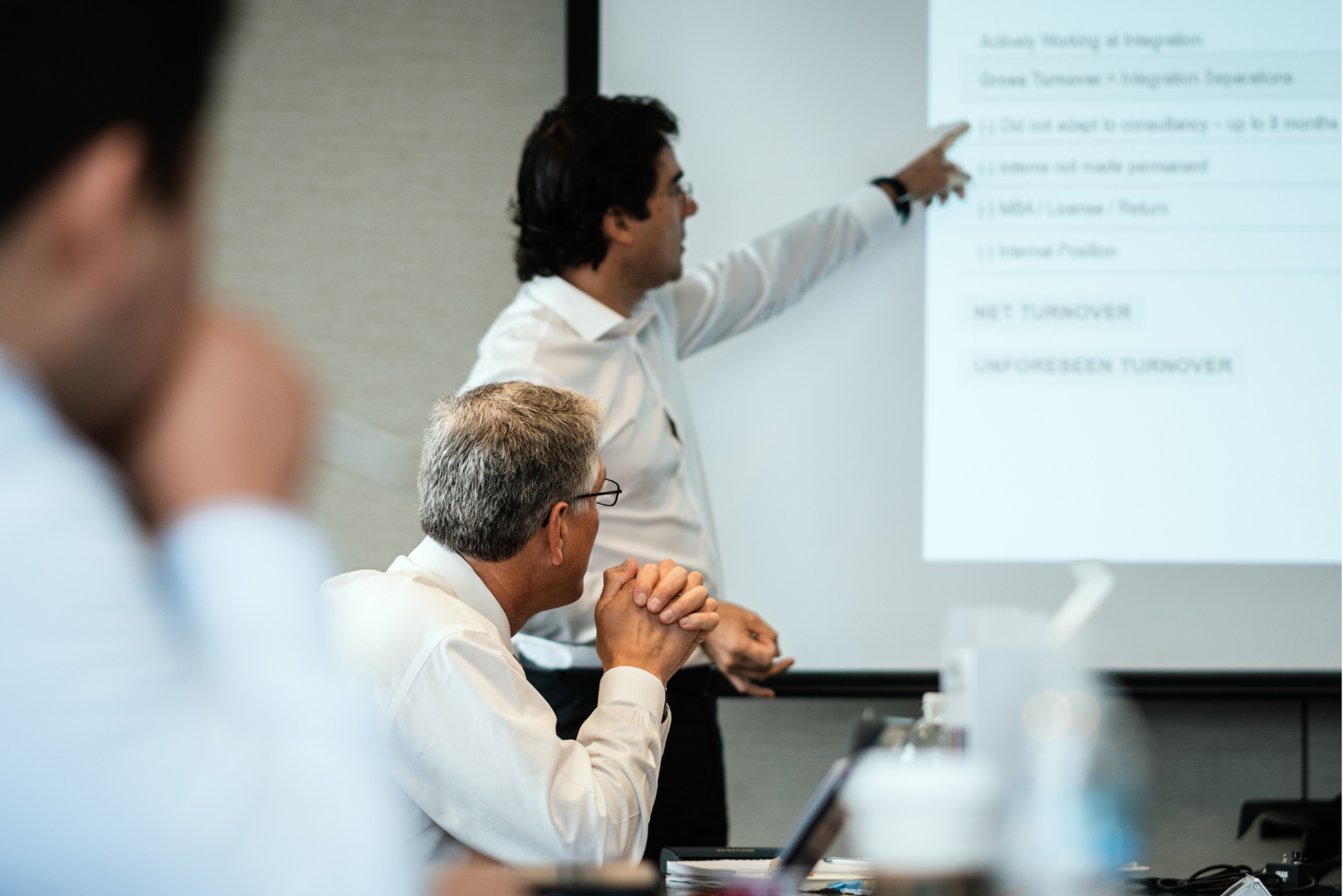 Man pointing at a presentation screen during a business meeting, teaching about risk mitigation.
