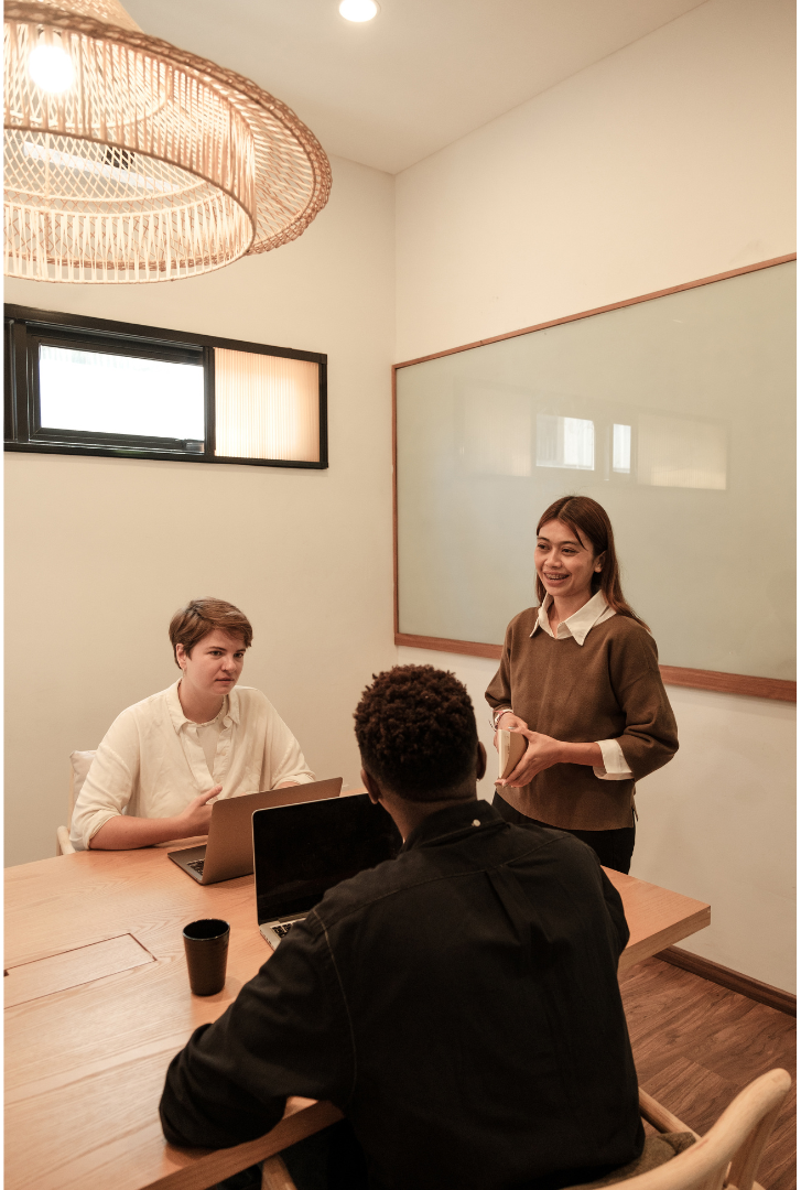 Three people in a bright office meeting room about HR compliance.