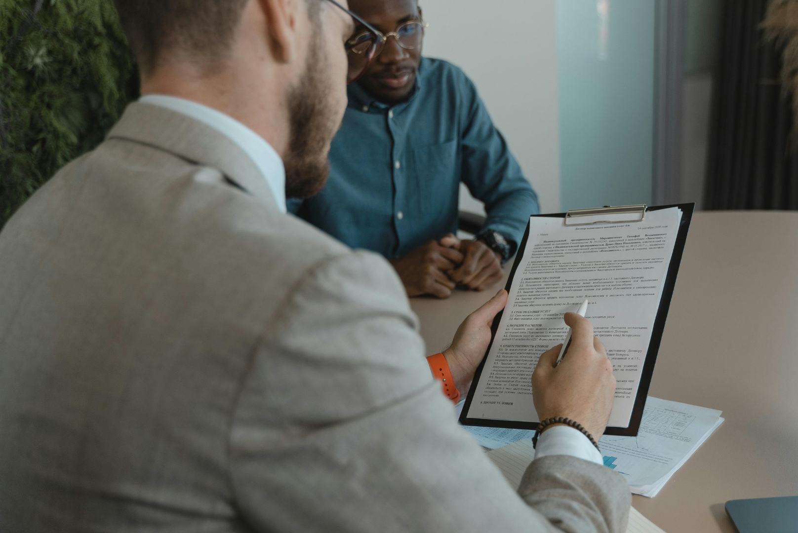 Man in suit pointing to document; interviewing another man representing HR Infrastructure 