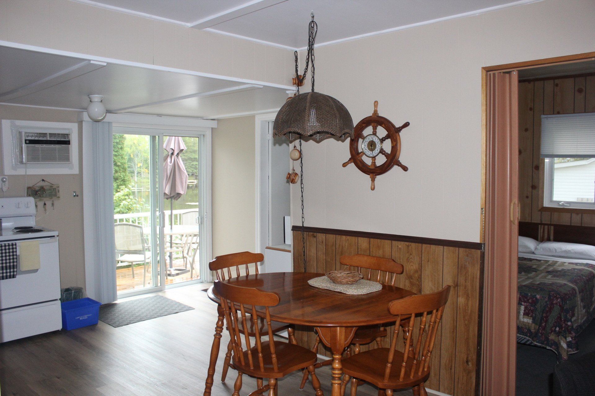 A dining room with a table and chairs and a ship 's wheel on the wall