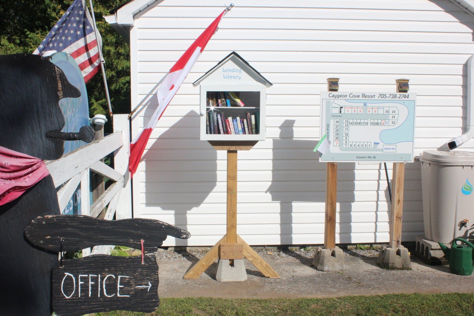 A black bear is sitting in front of a white building with a sign that says office