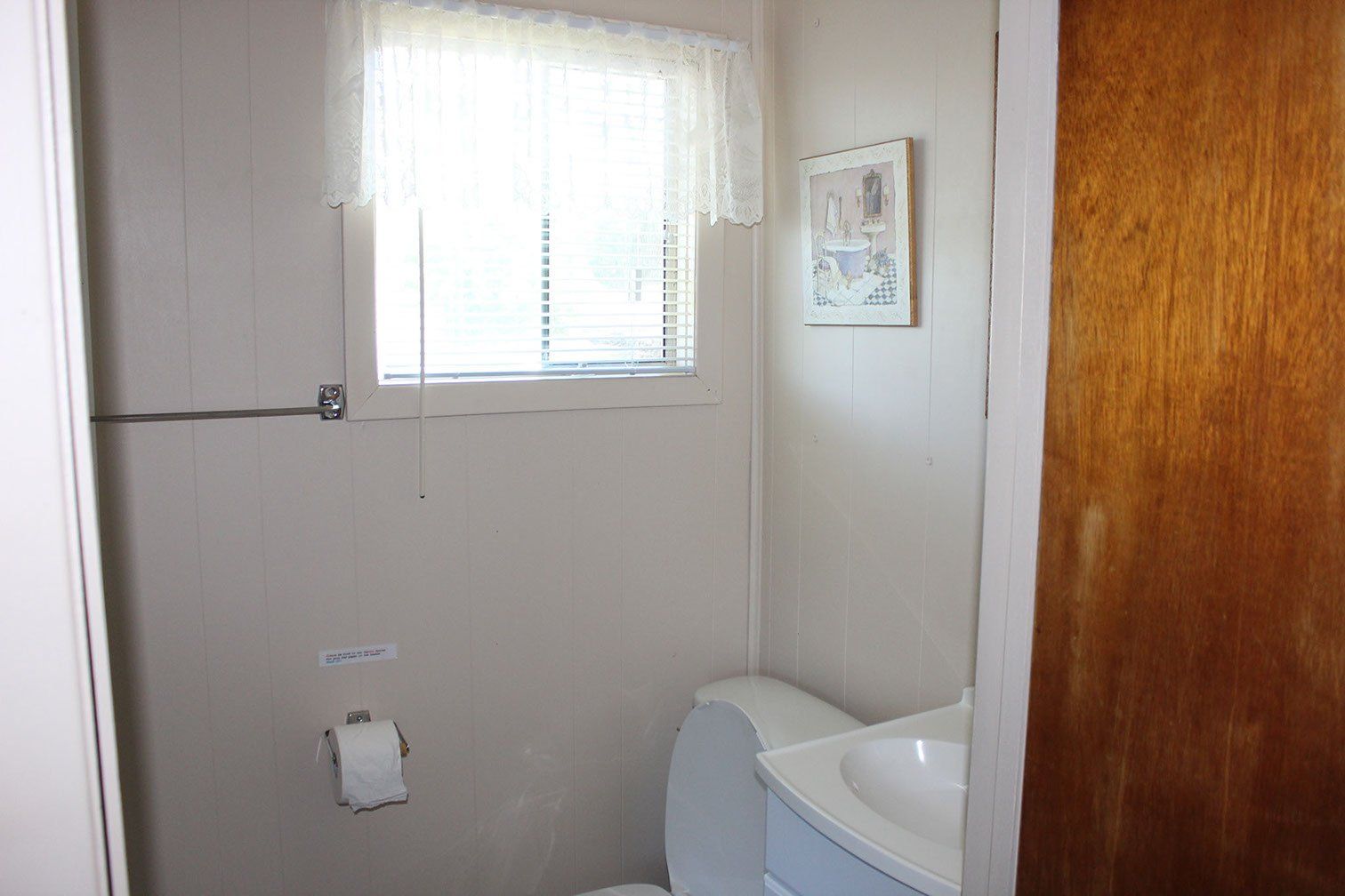 A bathroom with a toilet , sink and window.