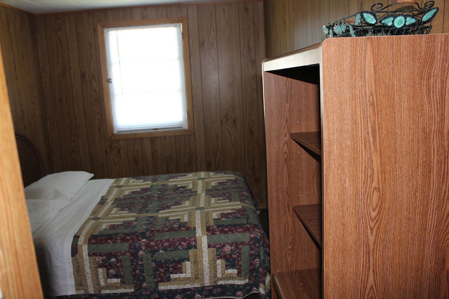 A bedroom with a bed , a window and a shelf.