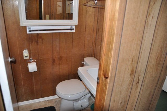 A bathroom with a toilet , sink and mirror.