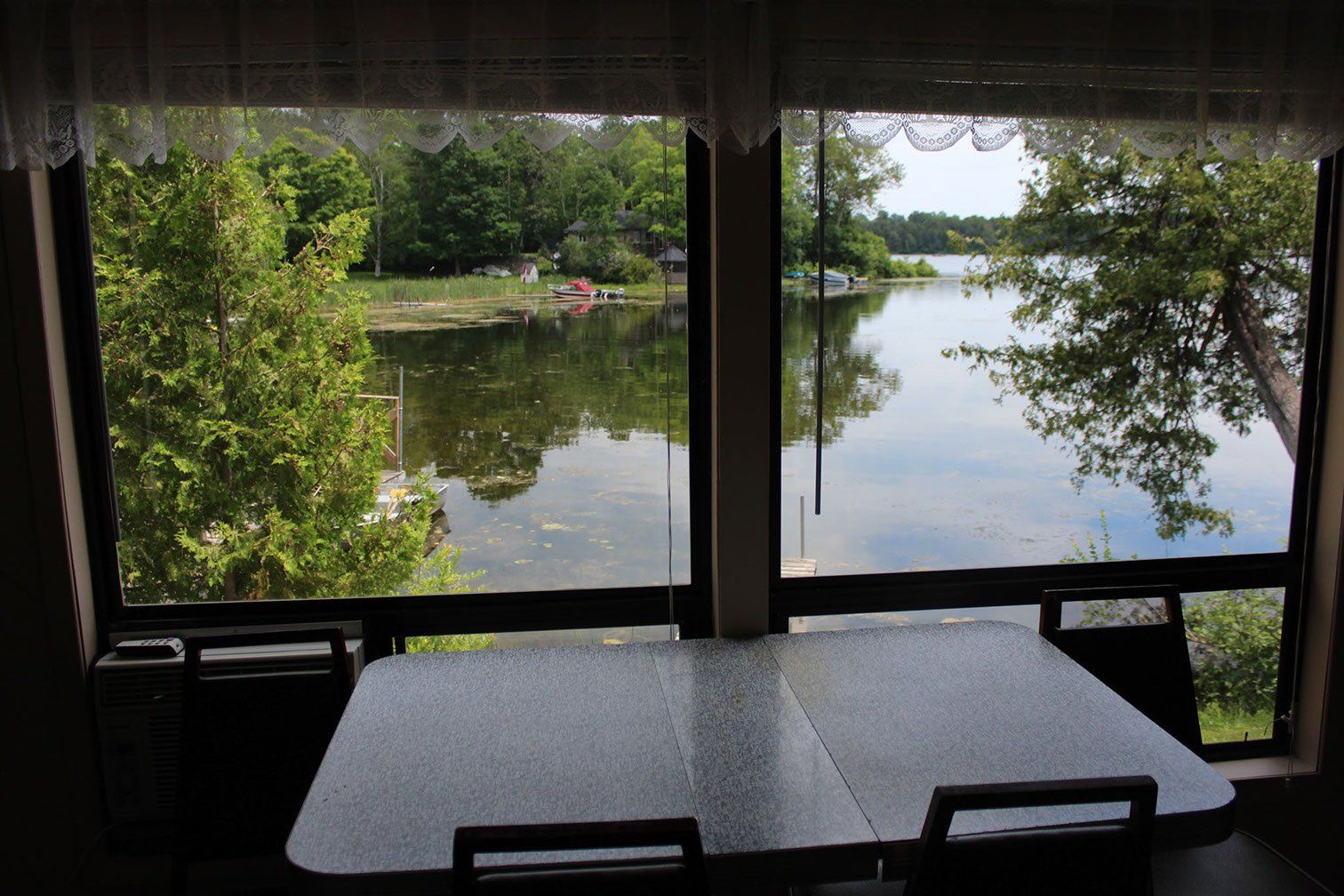 A table and chairs in front of a window overlooking a lake