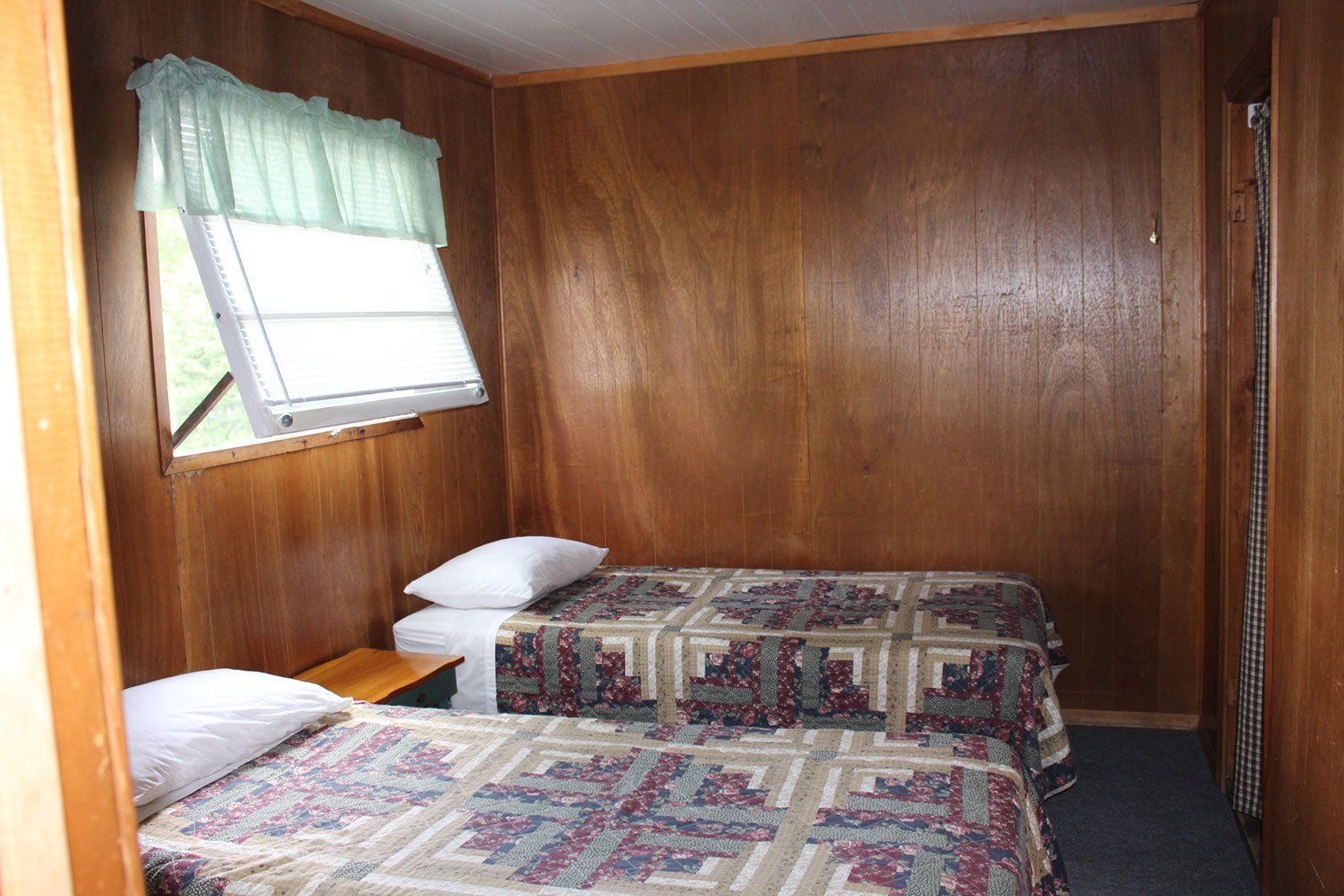 A bedroom with two beds and a window.