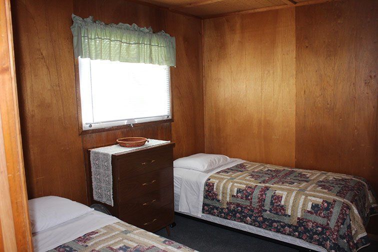 A bedroom with two beds , a dresser and a window.