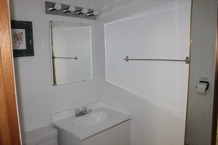 A bathroom with a sink , toilet , mirror and towel rack.