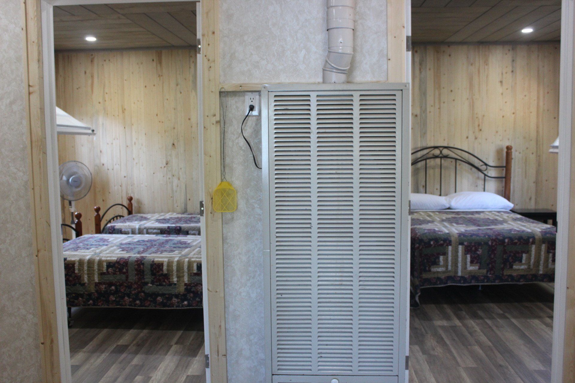 A bedroom with two beds , a closet and a fan.