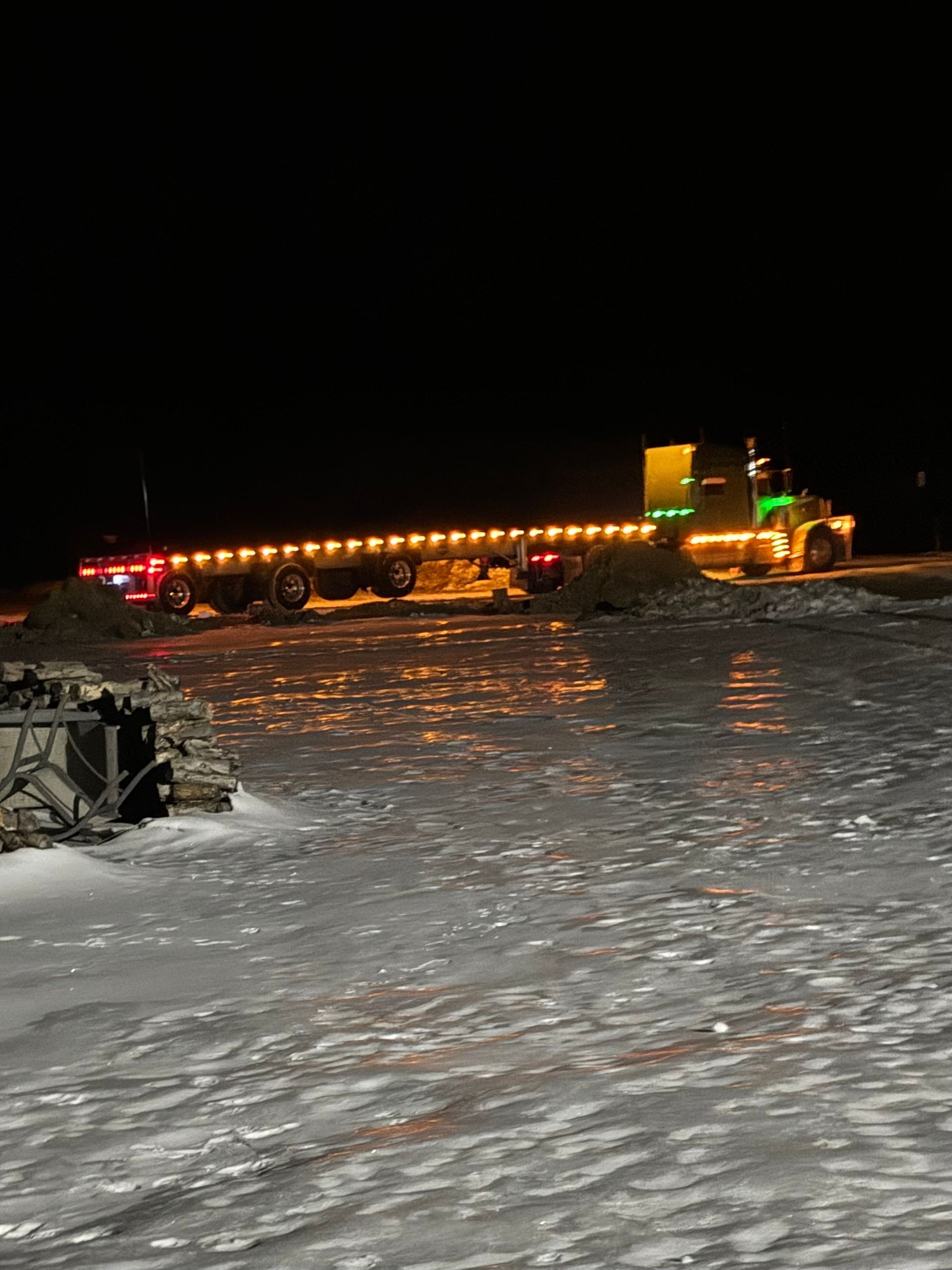 A truck is driving through a snowy field at night.