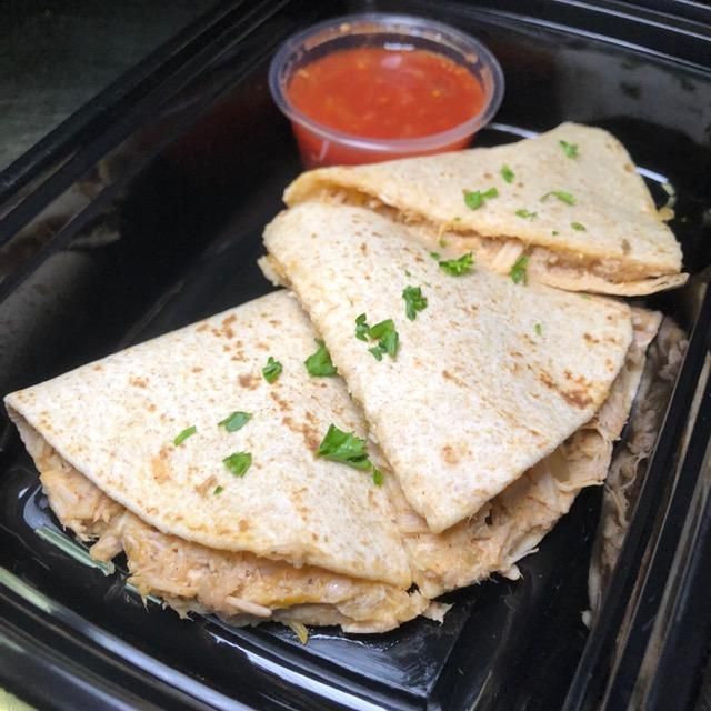 A tray of quesadillas next to a cup of salsa