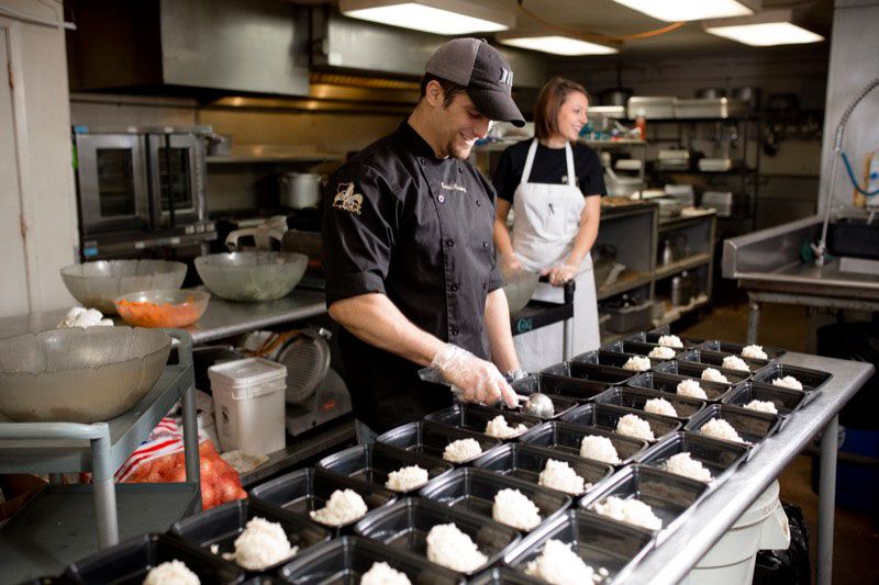 A man and a woman are preparing food in a kitchen.