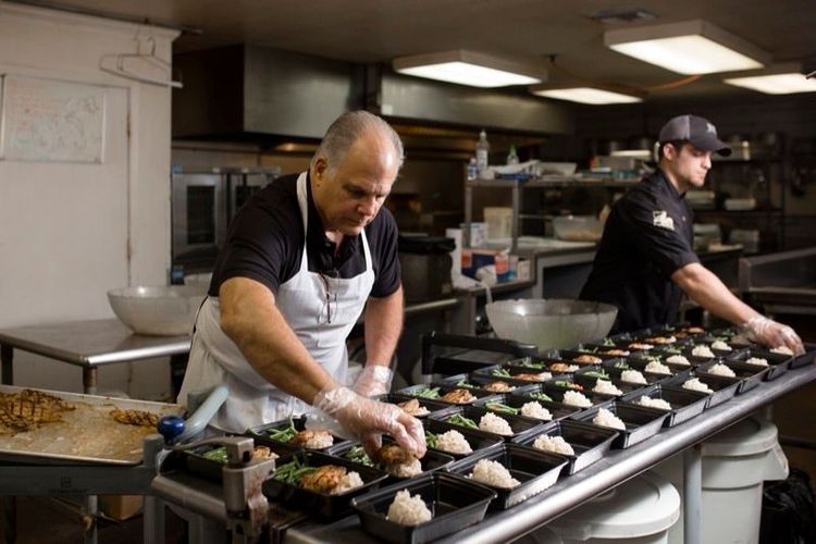 Two men are preparing food in a kitchen.