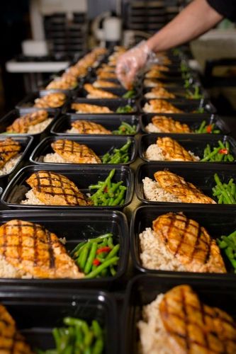 A person is preparing meals in plastic containers in a kitchen.