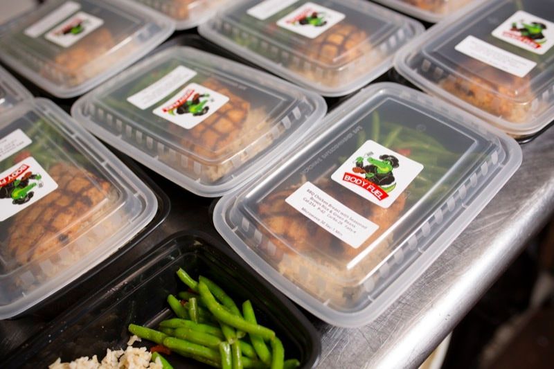 A bunch of plastic containers filled with food on a table.