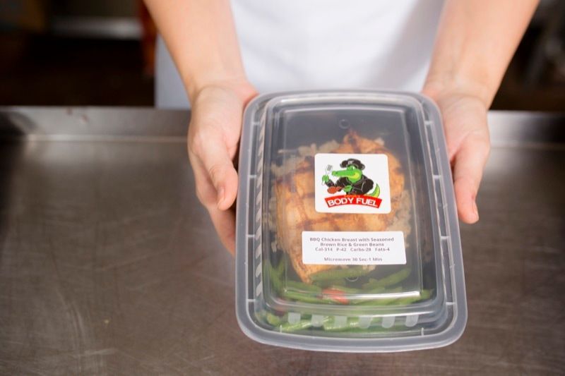A person is holding a plastic container with food in it.
