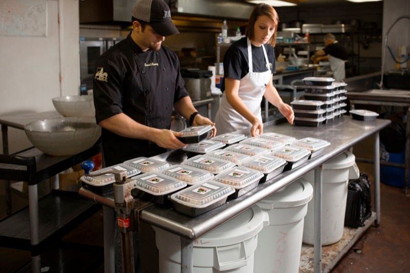 A man and a woman are preparing food in a kitchen.