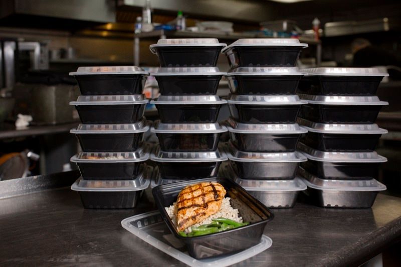 A stack of plastic containers filled with food on a counter.