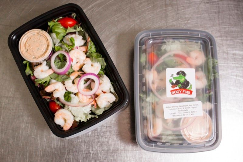 A salad in a plastic container next to a salad in a plastic container.
