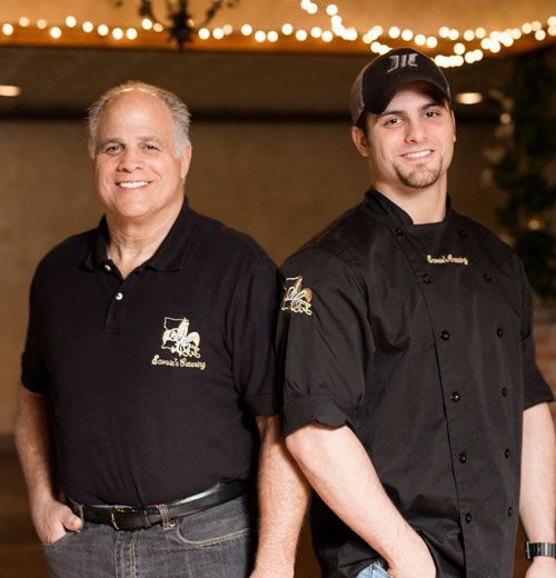 Two men standing next to each other one of whom is wearing a hat with the letter j on it