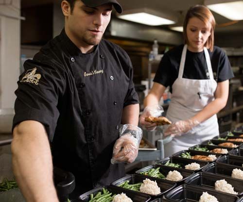 A man and a woman are preparing food in a kitchen.