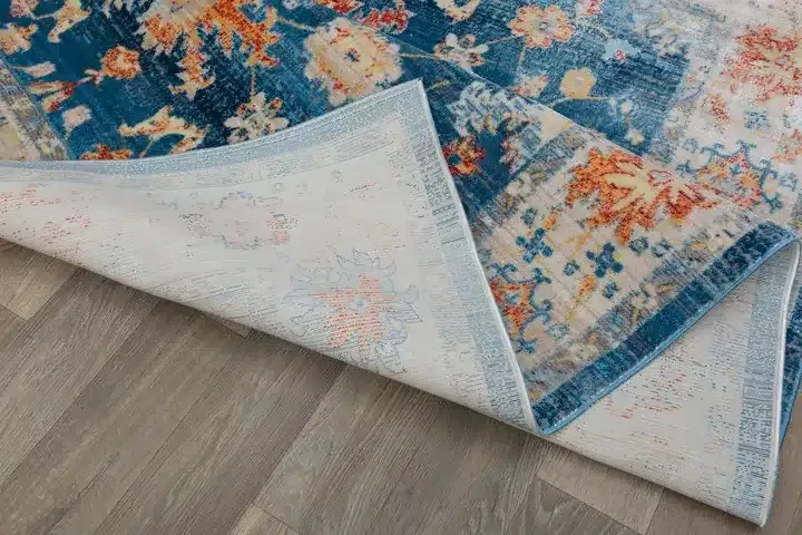 A blue and orange rug is laying on a wooden floor.