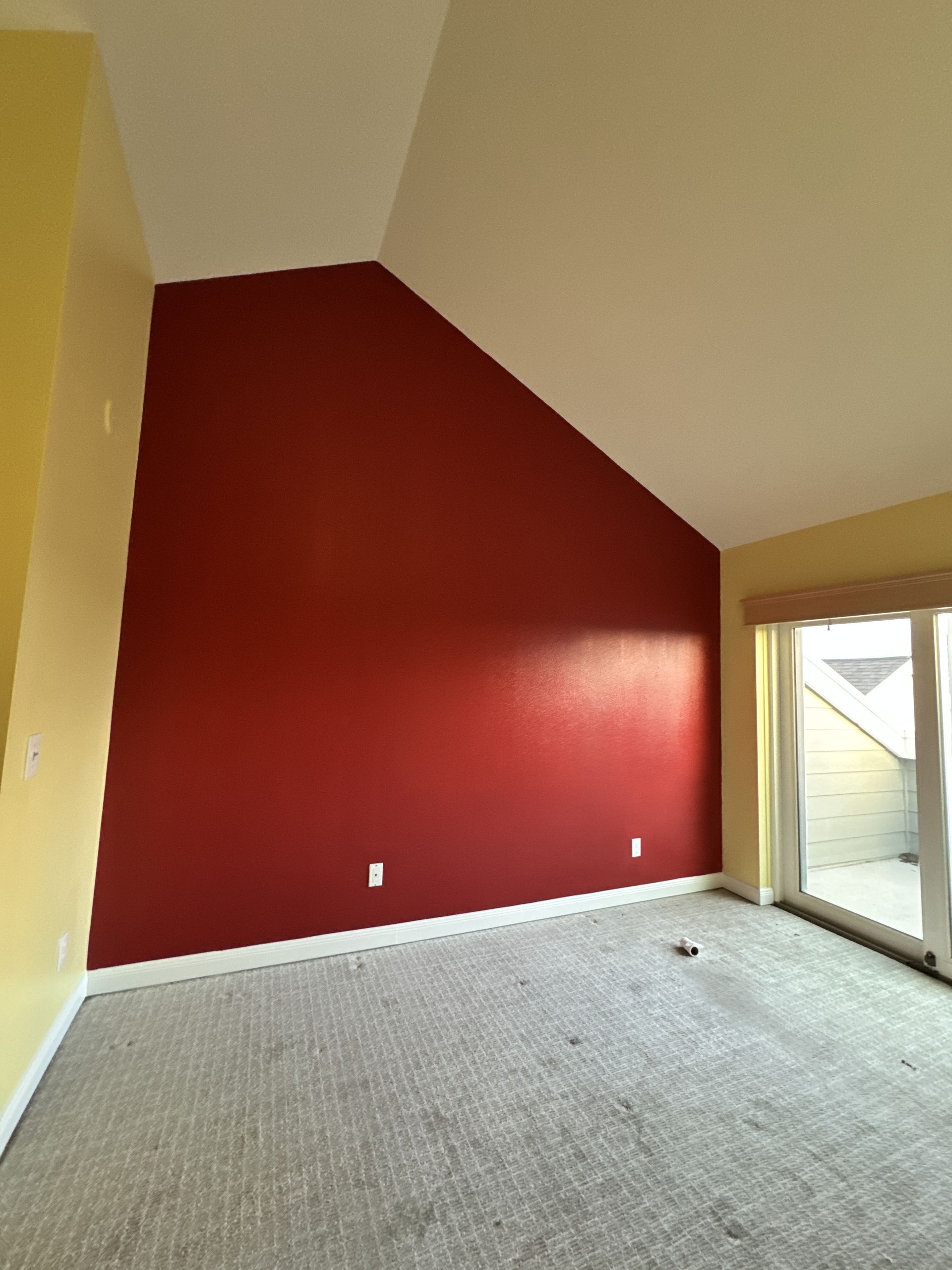 An empty living room with red walls and a vaulted ceiling.