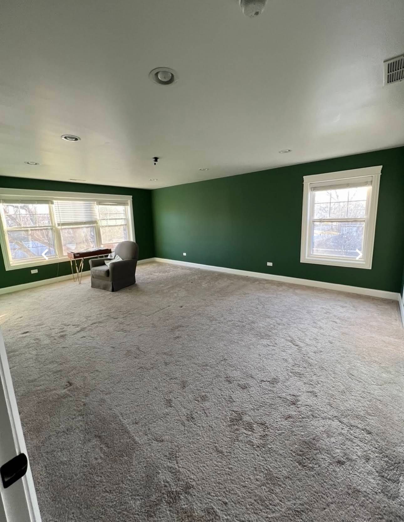 An empty living room with green walls and a carpeted floor.