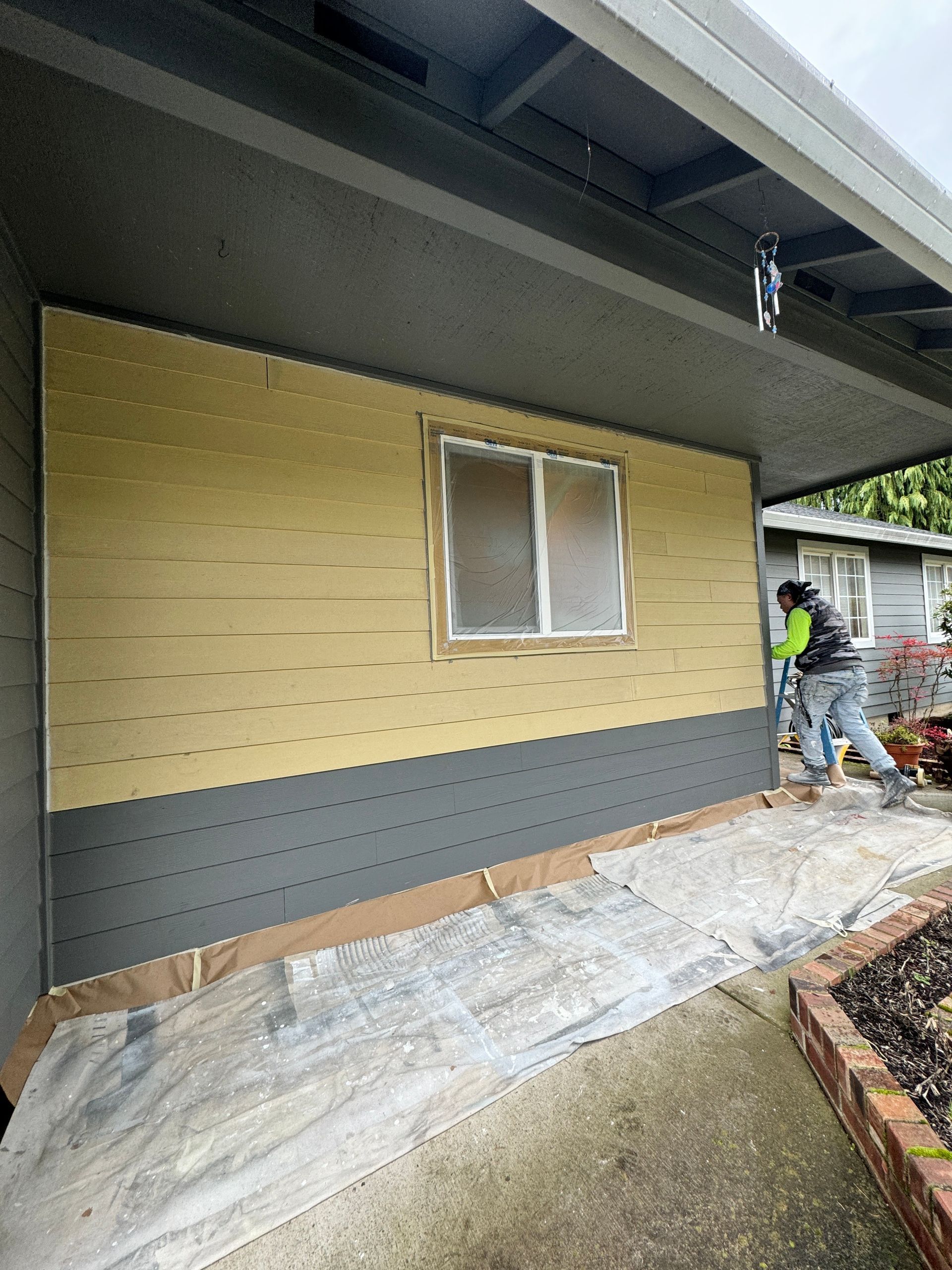 A man is installing siding on the side of a house.