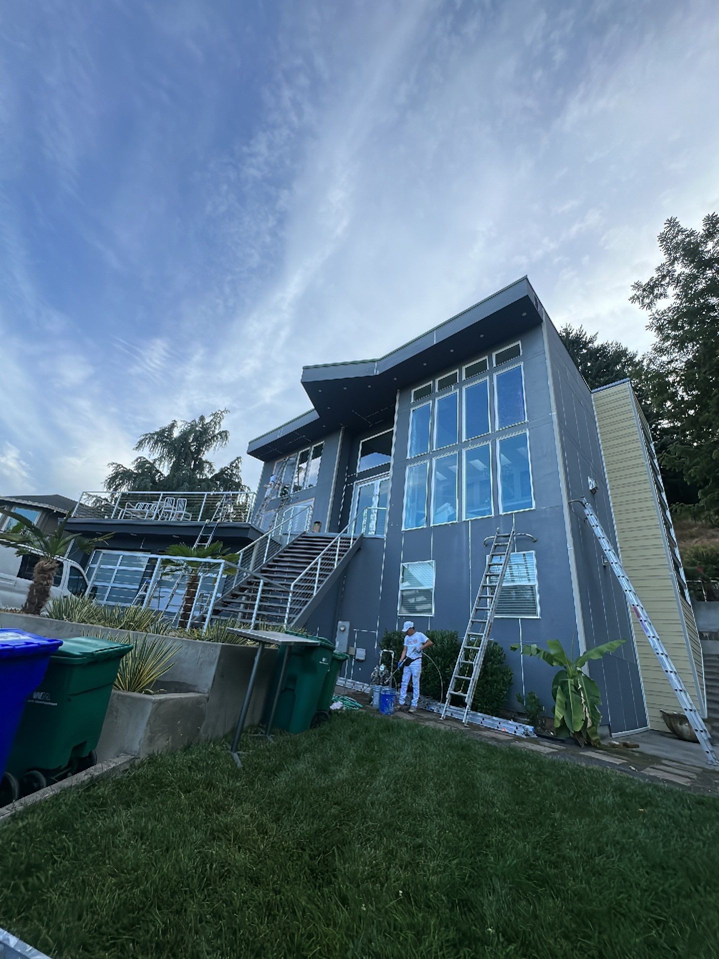 A man is painting the side of a large house.