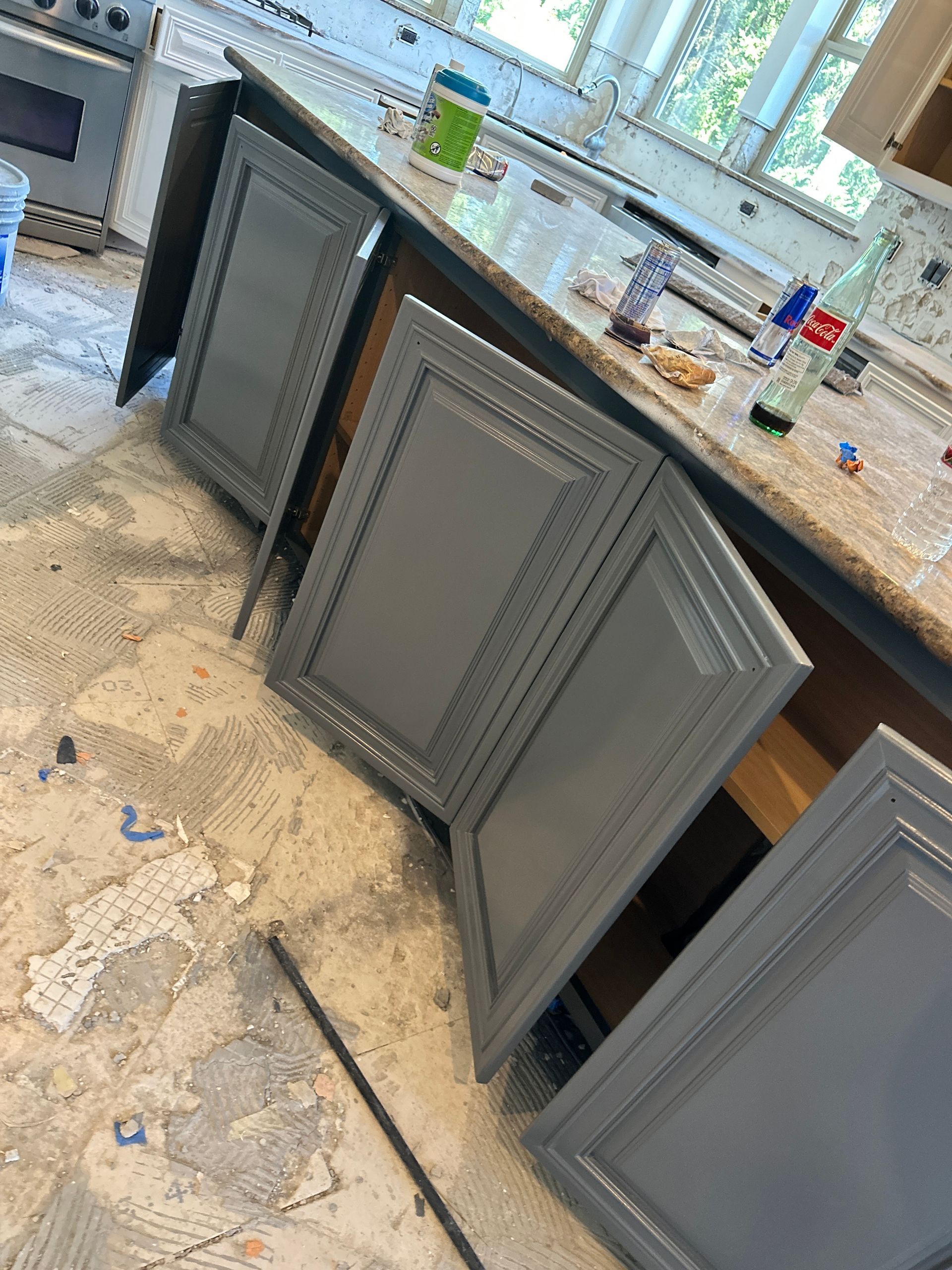 A kitchen with gray cabinets and a granite counter top.