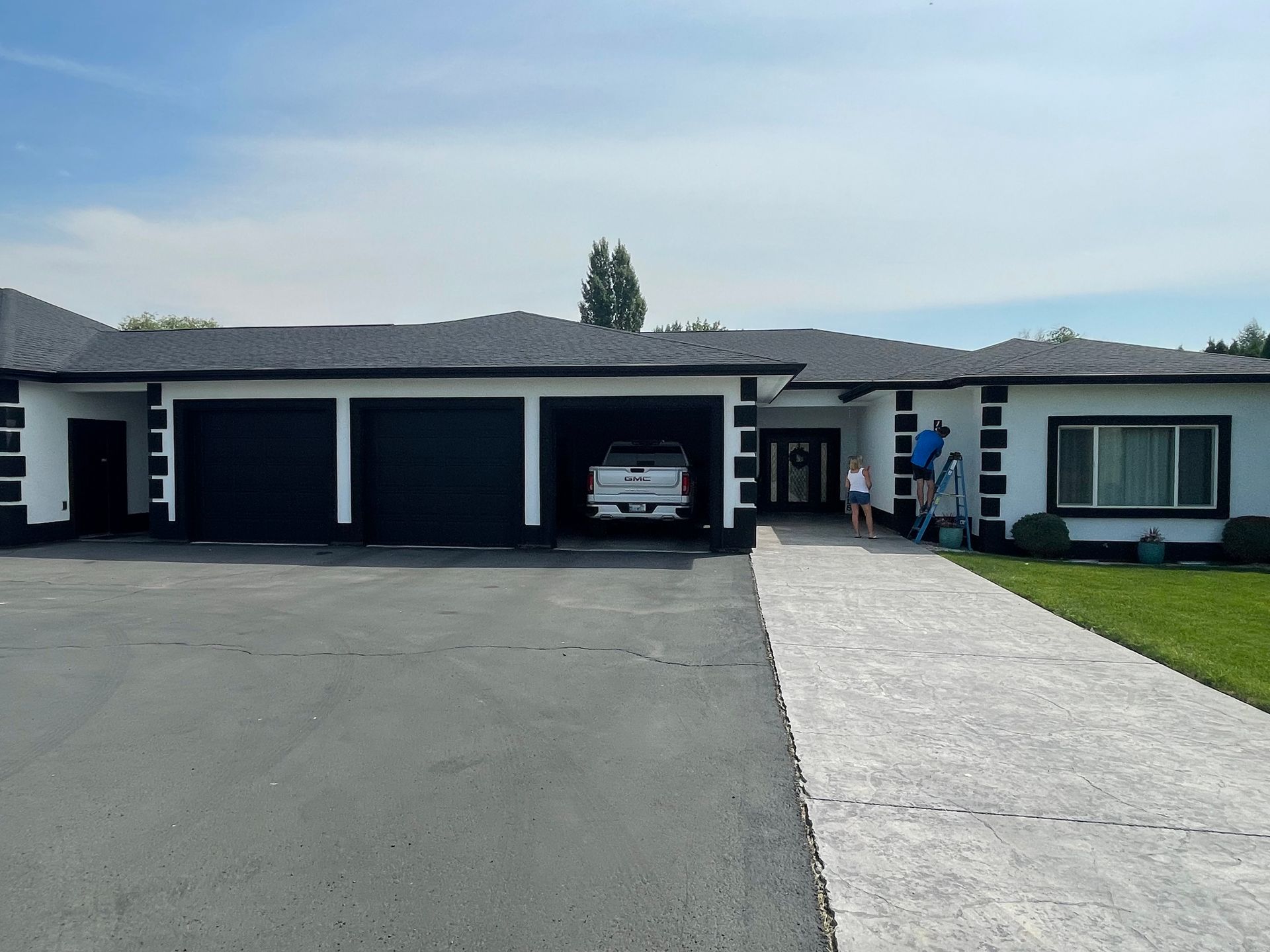 A white house with black garage doors and a white truck parked in front of it.