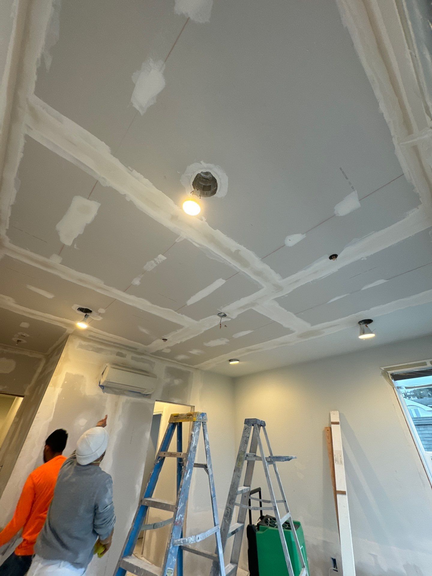A man is standing next to a ladder in a room.