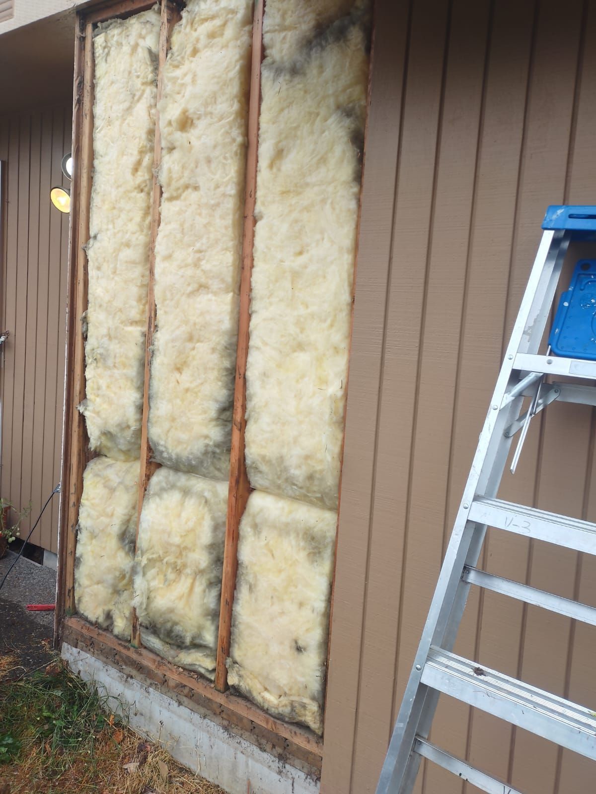 A ladder is sitting next to a wall with insulation on it.