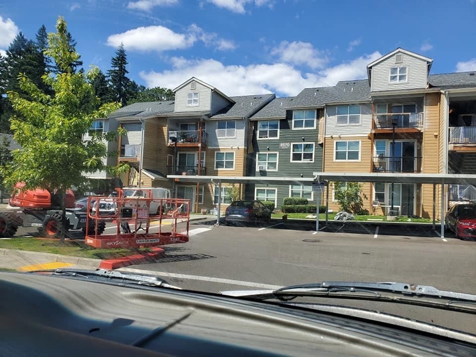 A large apartment building with a covered parking lot in front of it.