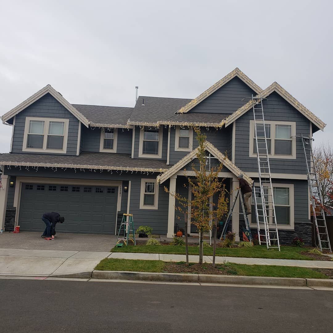 A large gray house with a ladder in front of it