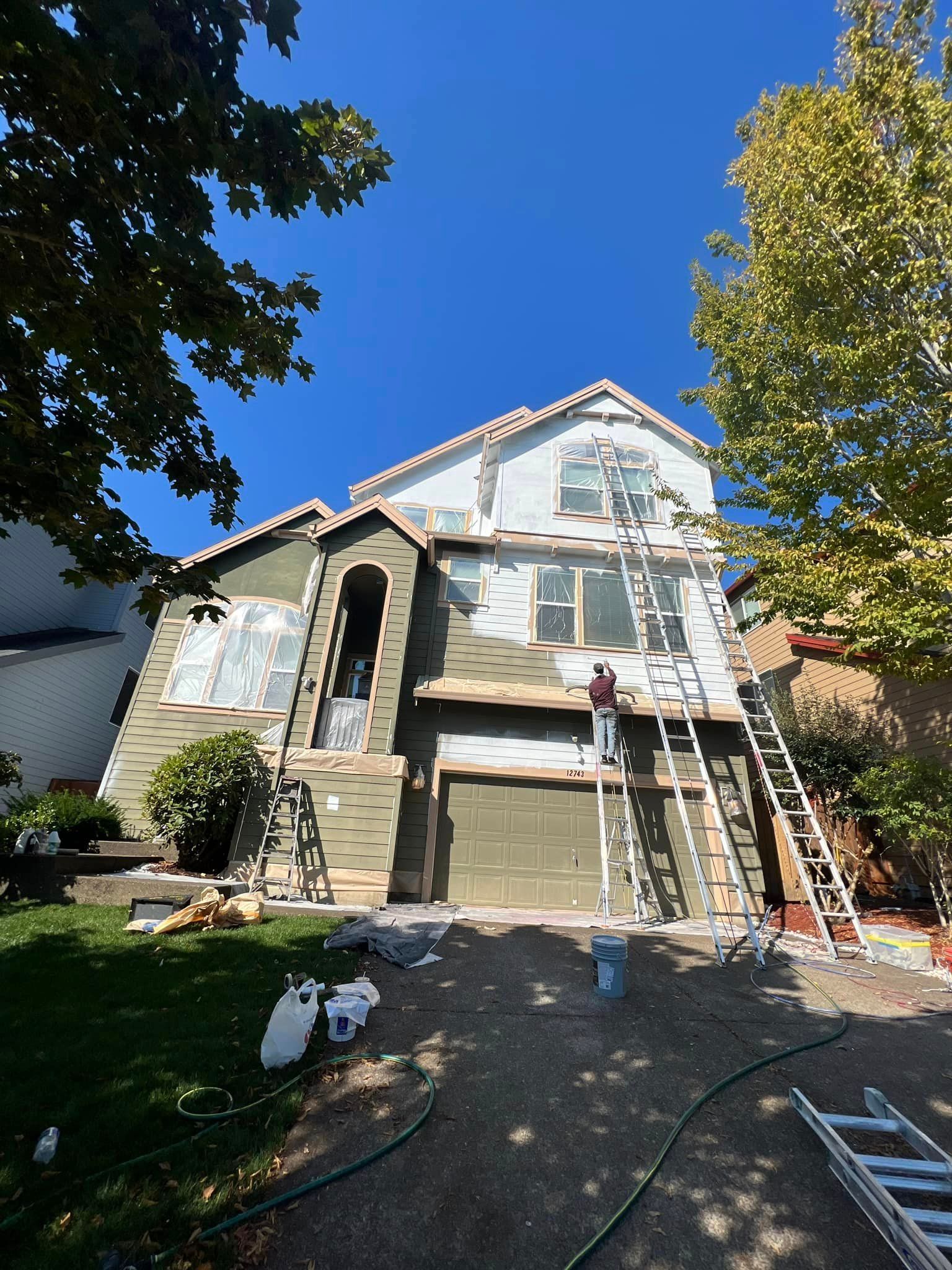 A house is being painted by a man on a ladder.