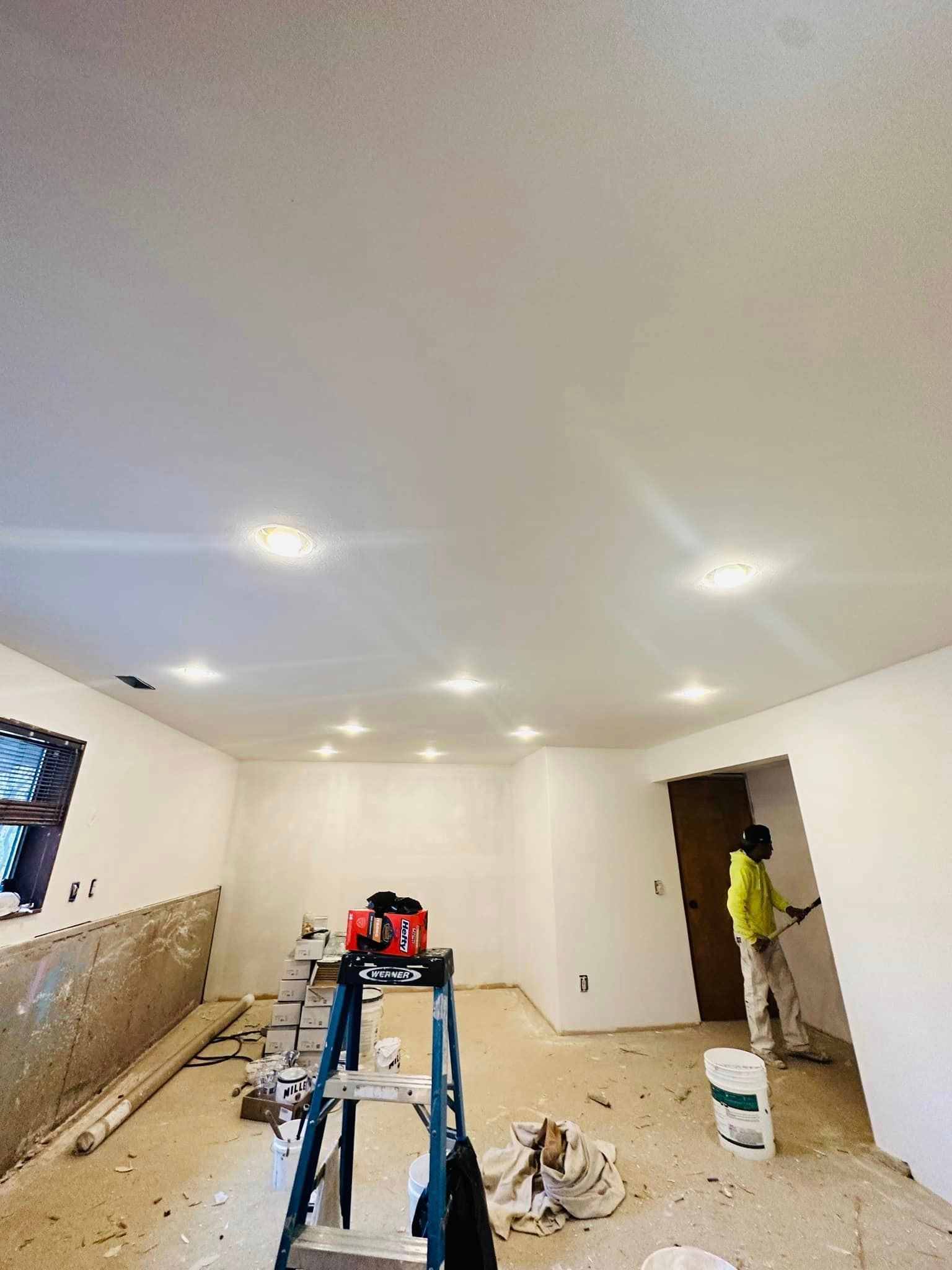 A man is painting the ceiling of a room.