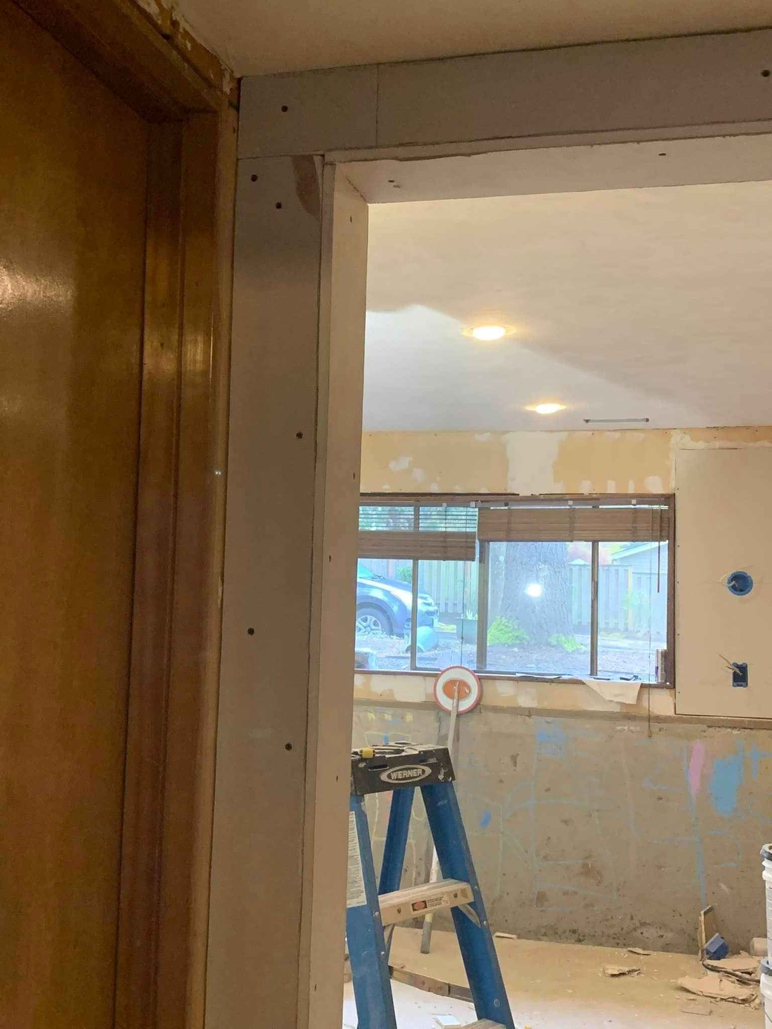 A blue ladder is sitting in a room next to a window.