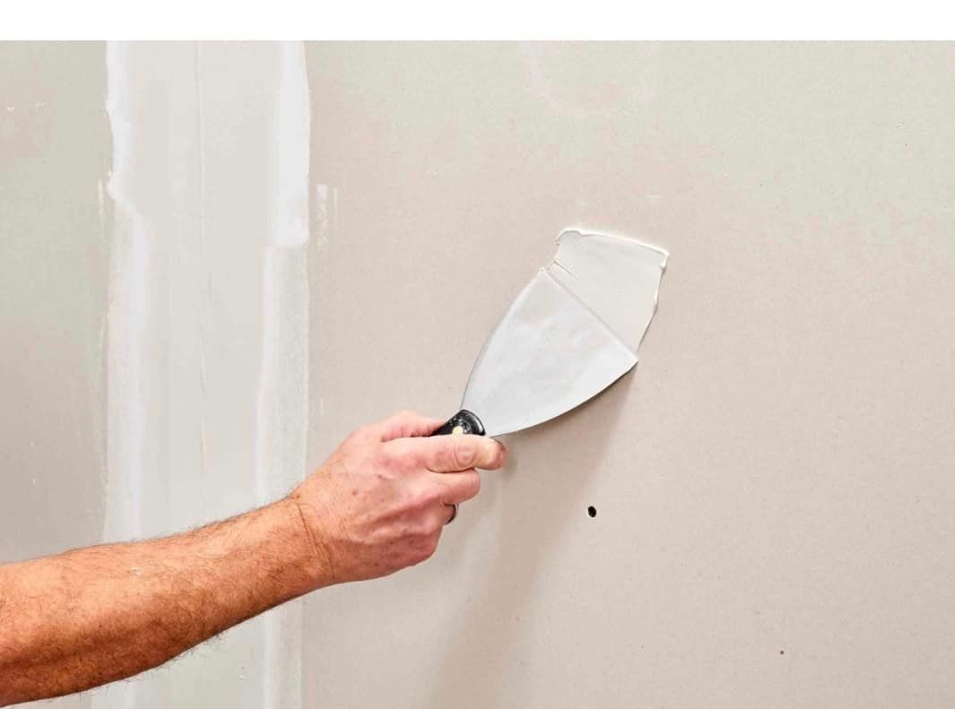 A person is plastering a wall with a spatula.