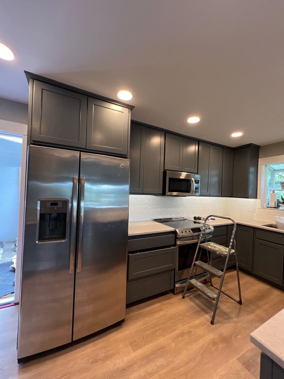 A kitchen with stainless steel appliances and gray cabinets.
