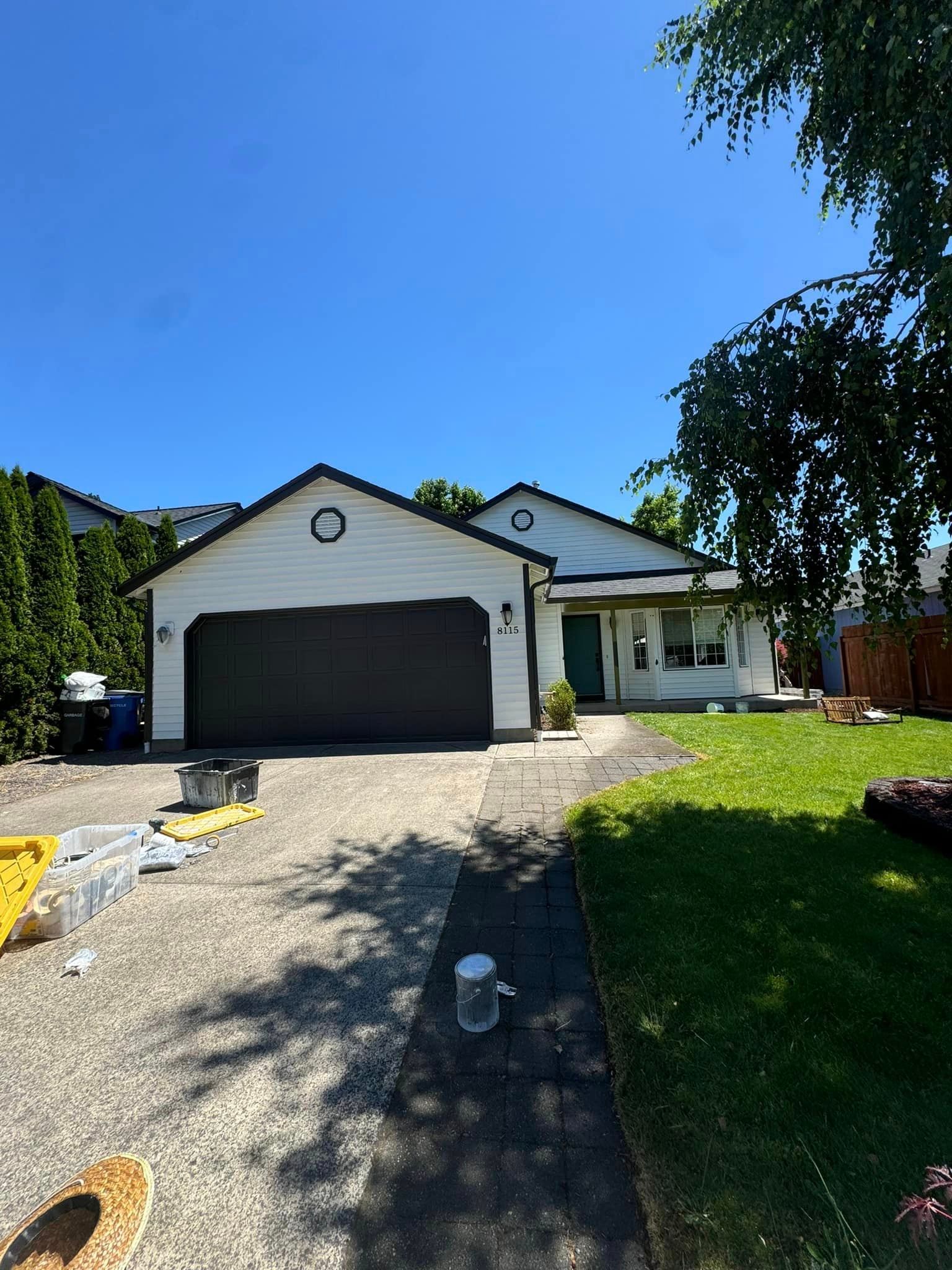 A white house with a black garage door is being painted