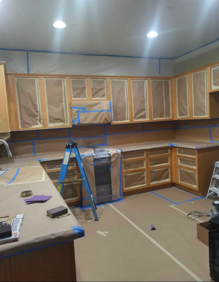 A kitchen with a ladder in the middle of it