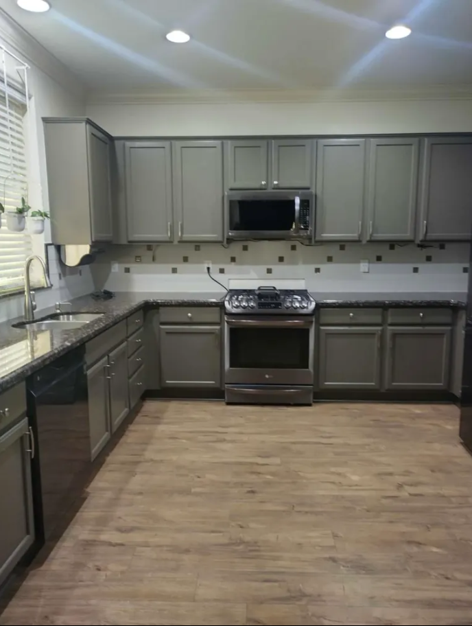 A kitchen with gray cabinets and stainless steel appliances