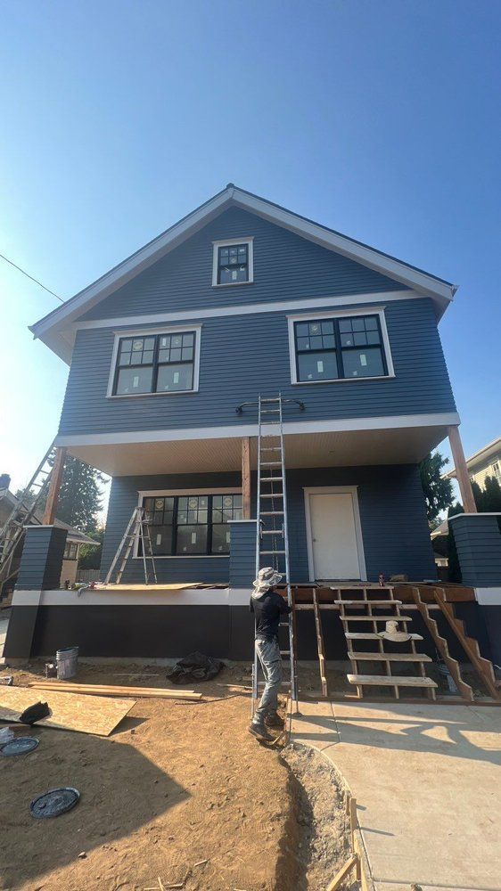 A man is standing in front of a blue house under construction.